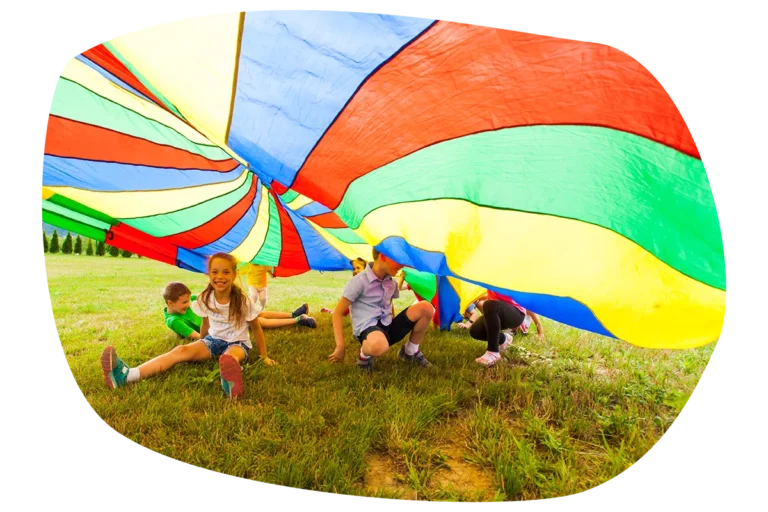 Kinder spielen gemeinsam unter einem Schwungtuch im Freien
